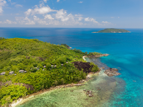 Aerial view of lush greenery meeting the turquoise sea with a distant island under a bright sky Victoria Mahe Island Seychelles. Aerial view of lush greenery meeting the turquoise sea with a distant island under a bright sky Victoria Mahe Island Seychelles.