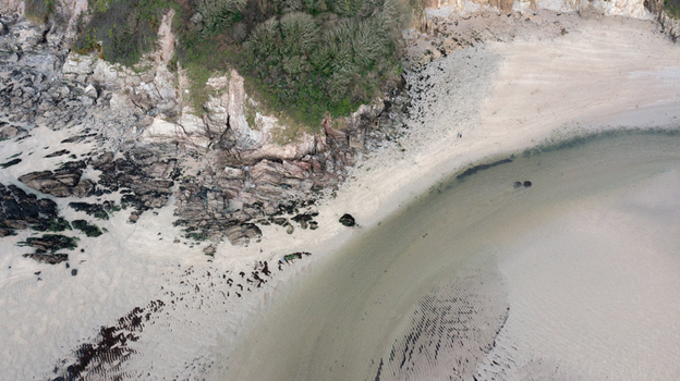 Aerial view of the sandy shores and rugged rocky cliffs at Mothecombe Beach with the river Erme flowing into the sea and people on the sand at Mothecombe Devon United Kingdom. Aerial view of the sandy shores and rugged rocky cliffs at Mothecombe Beach with the river Erme flowing into the sea and people on the sand at Mothecombe Devon United Kingdom.