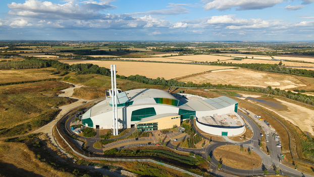 Aerial view of the Energy Recovery Facility with its curved roof and tall chimneys surrounded by agricultural fields in Bicester England United Kingdom.