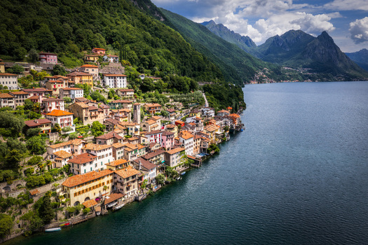 Aerial view of the historic village of Gandria nestled on the steep slopes of Lake Lugano featuring colorful houses lush green mountains and calm blue water in Lugano Ticino Switzerland.