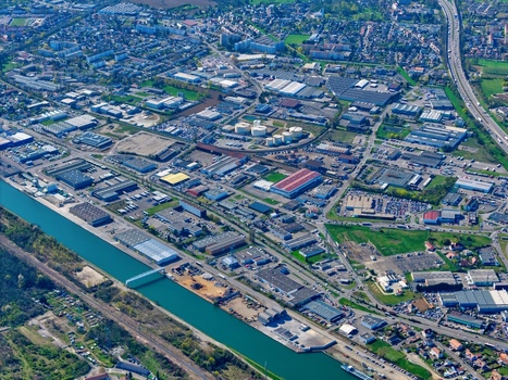 Aerial view of the contrasting landscapes with industrial buildings and a canal cutting through the urban fabric Sausheim Grand Est France.
