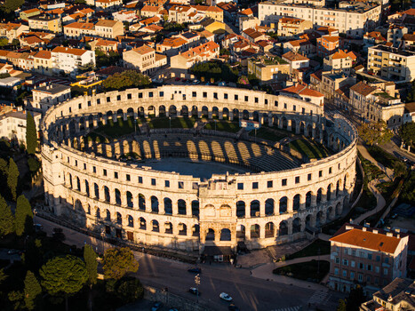 Aerial view of the ancient Roman amphitheater stands in stark contrast to the surrounding modern city bathed in the warm glow of the setting sun Pula Istria County Croatia.