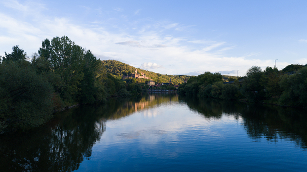 Aerial view of Wertheim Castle overlooking the Main river with lush trees calm water and a clear blue sky in Wertheim Baden Wurttemberg Germany. Aerial view of Wertheim Castle overlooking the Main river with lush trees calm water and a clear blue sky in Wertheim Baden Wurttemberg Germany.