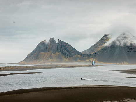 Aerial view of Vestrahorn mountain with a kitesurfer gliding across the shallow water near the sandy beach under a dramatic cloudy sky in Sveitarfelagid Hornafjordur Iceland. Aerial view of Vestrahorn mountain with a kitesurfer gliding across the shallow water near the sandy beach under a dramatic cloudy sky in Sveitarfelagid Hornafjordur Iceland.