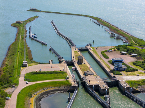 Aerial view of the Lorentzsluizen lock complex with water gates and piers surrounded by green embankments Kornwerderzand Friesland Netherlands.