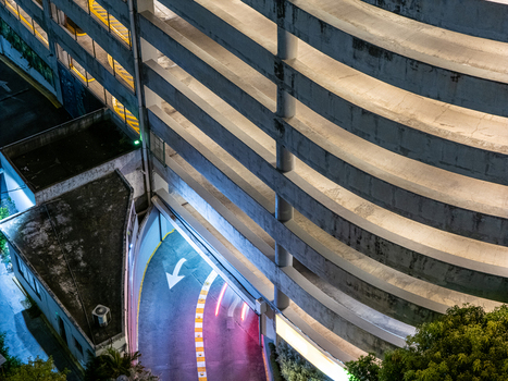 Aerial view of a curved concrete parking garage ramp illuminated at night with light trails from a vehicle and a directional arrow in Santo Domingo Distrito Nacional Dominican Republic. Aerial view of a curved concrete parking garage ramp illuminated at night with light trails from a vehicle and a directional arrow in Santo Domingo Distrito Nacional Dominican Republic.