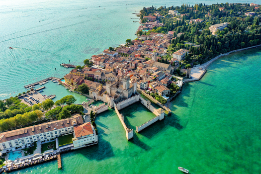 Aerial view of Castello Scaligero di Sirmione with its medieval fortifications and historic town surrounded by the turquoise waters of Lake Garda in Sirmione Lombardia Italy.