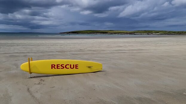 View of a yellow rescue surfboard on the beach in Ireland.