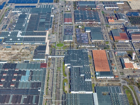 Aerial view of sprawling industrial complex with geometric patterns and a mix of grey and orange roofs under the vast sky Sausheim Grand Est France.