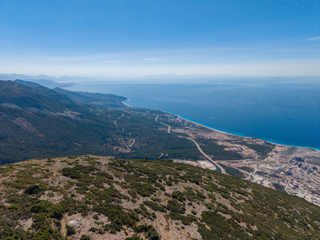 Aerial view of Bregdet.al Llogara Pass with winding roads descending towards the Ionian Sea coastline under a clear blue sky in Llogara Vlore County Albania. Aerial view of Bregdet.al Llogara Pass with winding roads descending towards the Ionian Sea coastline under a clear blue sky in Llogara Vlore County Albania.