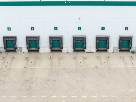 Aerial view of a logistics warehouse with numbered loading bays and green dock shelters in Warszawa Wojewodztwo mazowieckie Poland. Aerial view of a logistics warehouse with numbered loading bays and green dock shelters in Warszawa Wojewodztwo mazowieckie Poland.