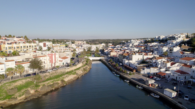 Aerial view of the historic town of Ferragudo with its white buildings riverfront and moored boats along the Arade River Ferragudo Faro District Portugal.