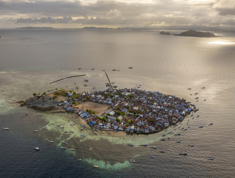 Aerial view of Pulau Mesa a densely populated island village surrounded by turquoise waters and numerous small boats in Kecamatan Komodo Nusa Tenggara Timur Indonesia. Aerial view of Pulau Mesa a densely populated island village surrounded by turquoise waters and numerous small boats in Kecamatan Komodo Nusa Tenggara Timur Indonesia.