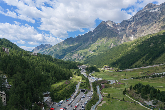 Aerial view of the mountain resort nestled in the Aosta Valley with winding roads forests and towering peaks under a blue sky in Breuil Cervinia Aosta Valley Italy. Aerial view of the mountain resort nestled in the Aosta Valley with winding roads forests and towering peaks under a blue sky in Breuil Cervinia Aosta Valley Italy.