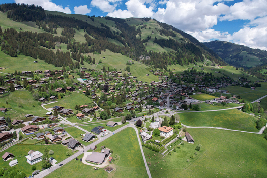 Aerial view of the traditional village of Rougemont with its historic church and wooden chalets nestled in the green Swiss Alps Rougemont Vaud Switzerland. Aerial view of the traditional village of Rougemont with its historic church and wooden chalets nestled in the green Swiss Alps Rougemont Vaud Switzerland.