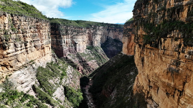 Aerial view of El Vergel canyon featuring dramatic layered rock cliffs lush green vegetation and a narrow canyon floor under a bright sky in Torotoro Potosi Department Bolivia. Aerial view of El Vergel canyon featuring dramatic layered rock cliffs lush green vegetation and a narrow canyon floor under a bright sky in Torotoro Potosi Department Bolivia.