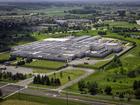 Aerial view of a large industrial facility with solar panels on the roof surrounded by green fields parking lots and roads in Volo Illinois United States. Aerial view of a large industrial facility with solar panels on the roof surrounded by green fields parking lots and roads in Volo Illinois United States.