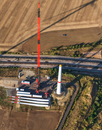 Aerial view of a wind turbine construction site featuring a tall red crane turbine blades and a tower base near the Schleenhain lignite open cast mine in Zwenkau Saxony Germany.
