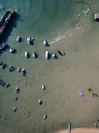 Aerial view of numerous small boats moored in the shallow turquoise waters of the harbor at low tide in Saint Ives Cornwall United Kingdom.
