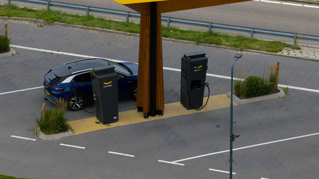 Krabbendijke Netherlands 28 June 2026 Aerial view of an electric vehicle charging at a Fastned station with modern charging pillars and a wooden canopy in a paved parking area. Krabbendijke Netherlands 28 June 2026 Aerial view of an electric vehicle charging at a Fastned station with modern charging pillars and a wooden canopy in a paved parking area.