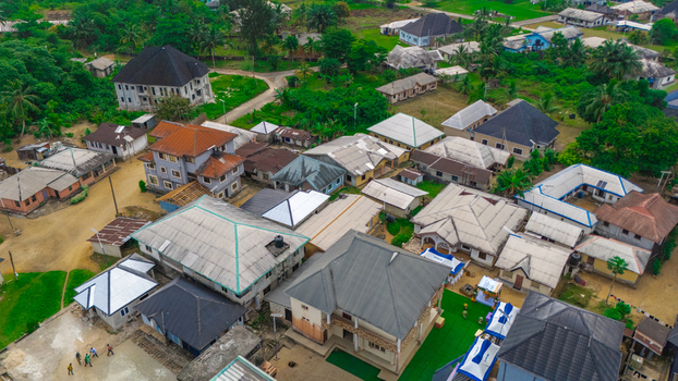 Aerial view of residential houses and buildings in a neighborhood with green trees and dirt roads in Minima Rivers Nigeria.
