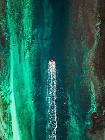 Aerial view of a boat cutting through the turquoise waters near Kåkernbrua the wake a stark white against the vibrant sea Kåkernbrua Nordland Norway. Aerial view of a boat cutting through the turquoise waters near Kåkernbrua the wake a stark white against the vibrant sea Kåkernbrua Nordland Norway.