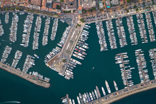 Aerial view of the marina in Antibes filled with yachts and boats docked along the piers with urban buildings and coastal roads in Antibes Provence Alpes Cote d Azur France. Aerial view of the marina in Antibes filled with yachts and boats docked along the piers with urban buildings and coastal roads in Antibes Provence Alpes Cote d Azur France.