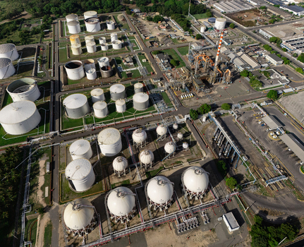 Aerial view of the industrial refinery complex with numerous white storage tanks pipeline networks and paved roads in Bajos de Haina San Cristobal Province Dominican Republic.