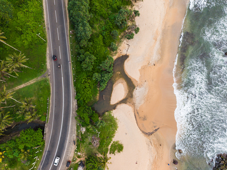 Aerial view of Dadalla beach with a coastal road running alongside lush tropical greenery and ocean waves in Galle Southern Province Sri Lanka. Aerial view of Dadalla beach with a coastal road running alongside lush tropical greenery and ocean waves in Galle Southern Province Sri Lanka.