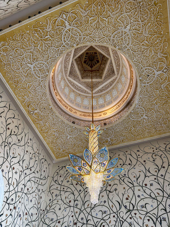 Abu Dhabi United Arab Emirates 15 October 2023 View of floral mosaic walls and an ornate chandelier hanging from the domed ceiling inside the Sheikh Zayed Grand Mosque.