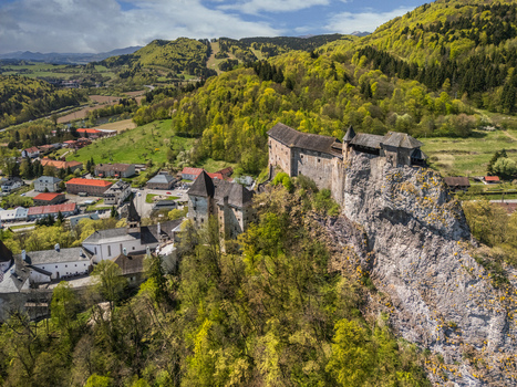 Aerial view of Orava Castle perched on a steep rocky cliff surrounded by lush green forests and a village in Dolny Kubin Zilinsky kraj Slovakia. Aerial view of Orava Castle perched on a steep rocky cliff surrounded by lush green forests and a village in Dolny Kubin Zilinsky kraj Slovakia.