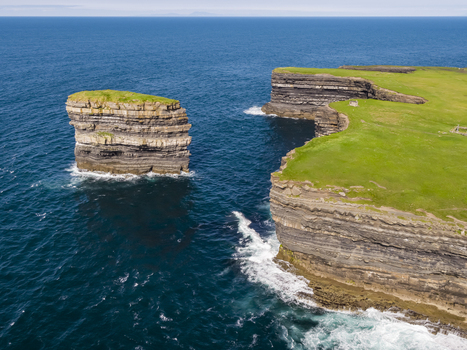 Aerial view of Dun Briste sea stack rising from the Atlantic Ocean near the dramatic cliffs of Downpatrick Head with lush green grass and layered rock formations County Mayo Ireland. Aerial view of Dun Briste sea stack rising from the Atlantic Ocean near the dramatic cliffs of Downpatrick Head with lush green grass and layered rock formations County Mayo Ireland.