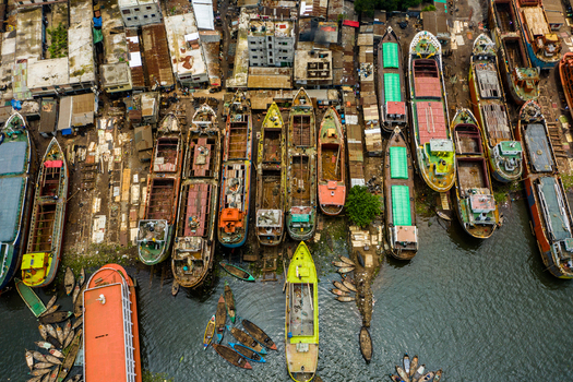 Aerial view of a busy shipyard featuring numerous cargo ships and small boats docked along the riverbank with industrial structures in the background Dhaka Dhaka Division Bangladesh.