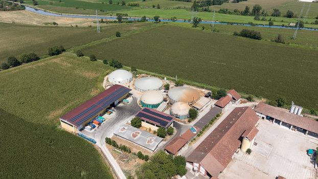 Aerial view of a biomethane production facility with circular digesters solar panels and agricultural buildings surrounded by green fields in Tavazzano con Villavesco Lombardy Italy.