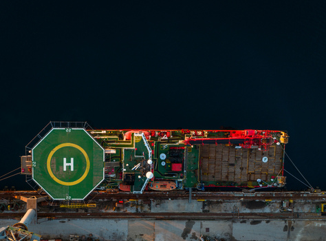 Aerial view of the Uljanik Shipyard in Pula Croatia featuring a supply vessel with a prominent helipad docked at the industrial pier. Aerial view of the Uljanik Shipyard in Pula Croatia featuring a supply vessel with a prominent helipad docked at the industrial pier.