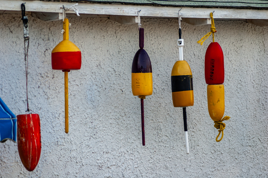 View of colorful weathered fishing buoys hanging against a white textured wall in Edgartown Massachusetts United States.