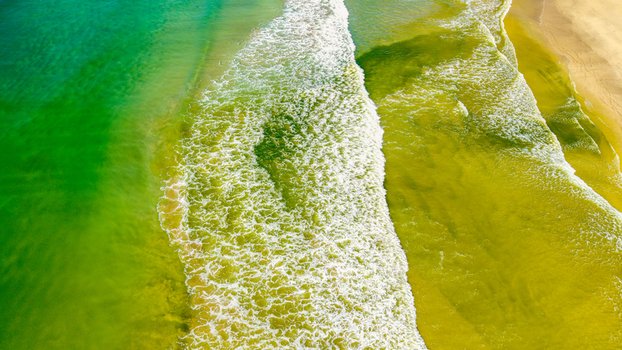 Aerial view of Hartenbos beach with vibrant green water and white waves crashing on the sandy shore in Mossel Bay Western Cape South Africa. Aerial view of Hartenbos beach with vibrant green water and white waves crashing on the sandy shore in Mossel Bay Western Cape South Africa.