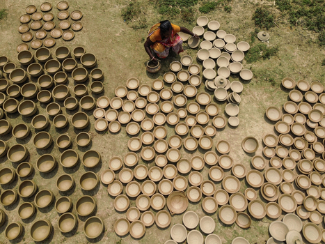 Joypurhat Bangladesh 28 September 2026 Aerial view of a woman arranging numerous handmade clay pots on the ground to dry in the sun. Joypurhat Bangladesh 28 September 2026 Aerial view of a woman arranging numerous handmade clay pots on the ground to dry in the sun.