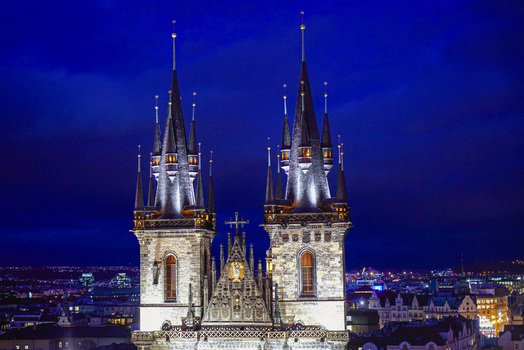 Aerial view of the Church of Our Lady before Tyn with its iconic gothic spires illuminated at night overlooking the historic city skyline of Prague Prague Czechia. Aerial view of the Church of Our Lady before Tyn with its iconic gothic spires illuminated at night overlooking the historic city skyline of Prague Prague Czechia.
