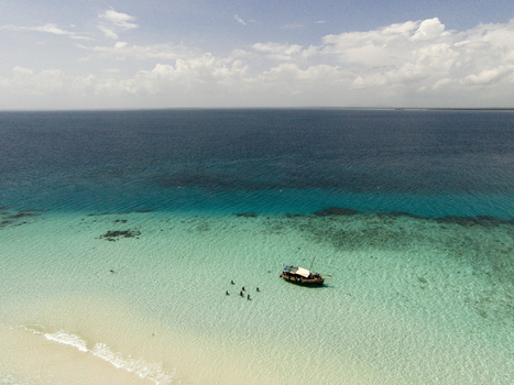 Aerial view of Kisite Mpunguti Marine National Park with a traditional boat and people swimming in turquoise waters in Kwale Kwale County Kenya. Aerial view of Kisite Mpunguti Marine National Park with a traditional boat and people swimming in turquoise waters in Kwale Kwale County Kenya.