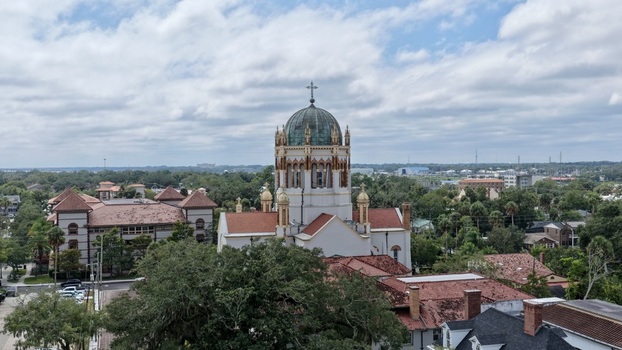 Aerial view of Memorial Presbyterian Church with its distinctive green dome and terracotta rooftops surrounded by lush trees in St. Augustine Florida United States.
