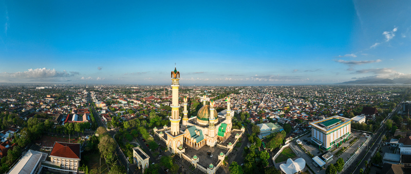 Aerial view of the Islamic Center NTB Hubbul Wathan Great Mosque with its green dome and tall minaret set amidst the urban landscape of Kecamatan Selaparang Nusa Tenggara Barat Indonesia. Aerial view of the Islamic Center NTB Hubbul Wathan Great Mosque with its green dome and tall minaret set amidst the urban landscape of Kecamatan Selaparang Nusa Tenggara Barat Indonesia.