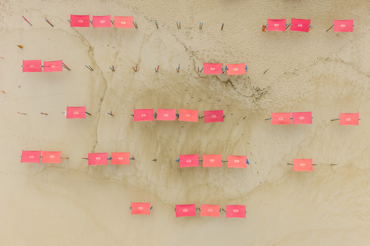 Aerial view of Praia de Sao Pedro de Moel featuring rows of pink sunshades arranged on the golden sand in Marinha Grande Leiria Portugal. Aerial view of Praia de Sao Pedro de Moel featuring rows of pink sunshades arranged on the golden sand in Marinha Grande Leiria Portugal.