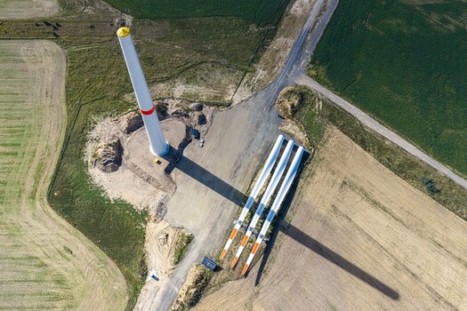 Aerial view of wind turbine components including a tower and three blades laid out at Windpark Forst Briesnig II on recultivated land in Forst Brandenburg Germany. Aerial view of wind turbine components including a tower and three blades laid out at Windpark Forst Briesnig II on recultivated land in Forst Brandenburg Germany.