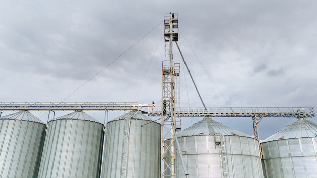 Aerial view of industrial silos stretching towards a cloudy sky their metallic surfaces reflecting the soft light Sremska Mitrovica Vojvodina Serbia. Aerial view of industrial silos stretching towards a cloudy sky their metallic surfaces reflecting the soft light Sremska Mitrovica Vojvodina Serbia.