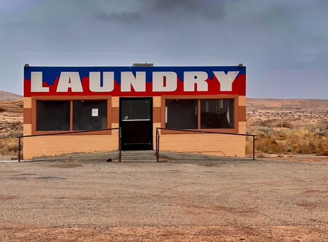 View of the iconic laundry building with its bold red and blue signage set against the vast desert landscape of Monument Valley Tribal Park in Oljato Monument Valley Utah United States.