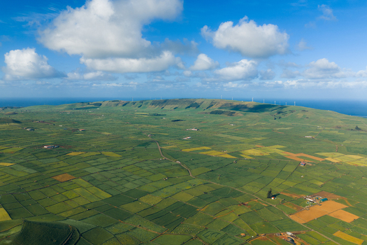 Aerial view of Pico Dona Joana geodesico overlooking a patchwork of green fields and wind turbines under a cloudy sky Feteira Acores Portugal.