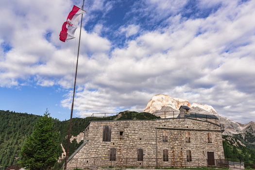 View of the historic stone fortification at Prato Piazza with a flag waving against the backdrop of the Dolomite mountains Dobbiaco Trentino Alto Adige Italy. View of the historic stone fortification at Prato Piazza with a flag waving against the backdrop of the Dolomite mountains Dobbiaco Trentino Alto Adige Italy.
