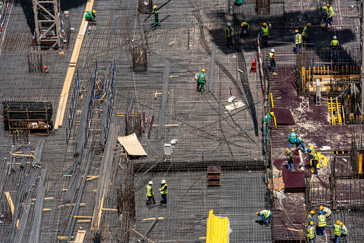 Aerial view of construction workers installing steel rebar reinforcement on a large building foundation site with various materials and equipment Dubai Dubai United Arab Emirates. Aerial view of construction workers installing steel rebar reinforcement on a large building foundation site with various materials and equipment Dubai Dubai United Arab Emirates.