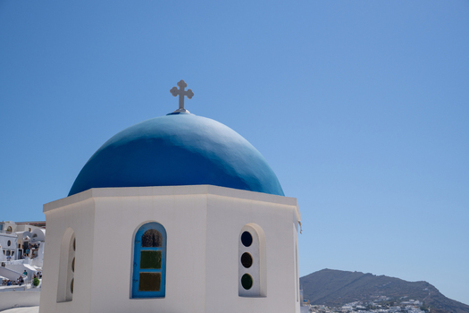 View of the Three Bells of Fira blue domed church with white walls under a clear blue sky in Fira Greece. View of the Three Bells of Fira blue domed church with white walls under a clear blue sky in Fira Greece.